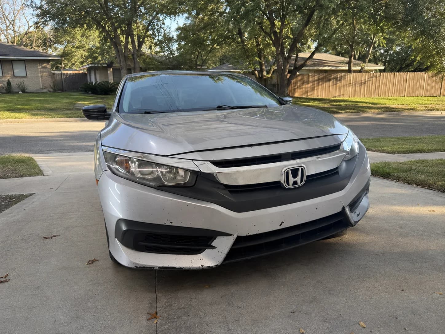 AI-generated rendition based on the silver Honda Civic source photo, including its visible bumper wear, placed in a residential driveway without dealer advertising