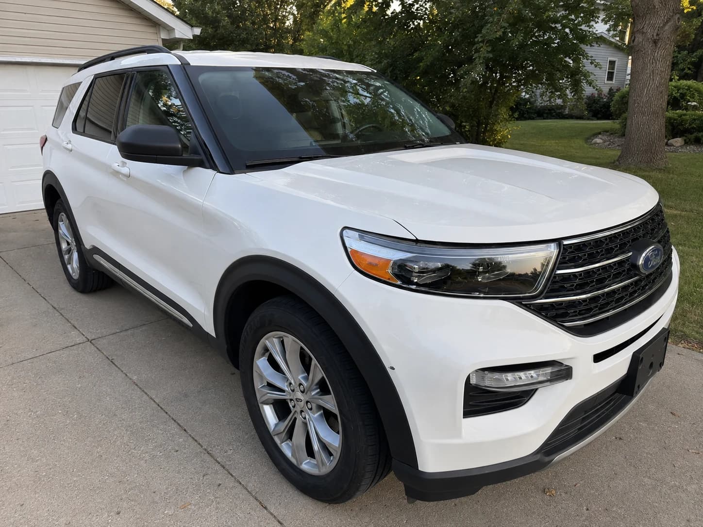 AI-generated rendition based on the white Ford Explorer XLT source photo, placed in a Minnesota home driveway without dealer advertising or windshield stickers